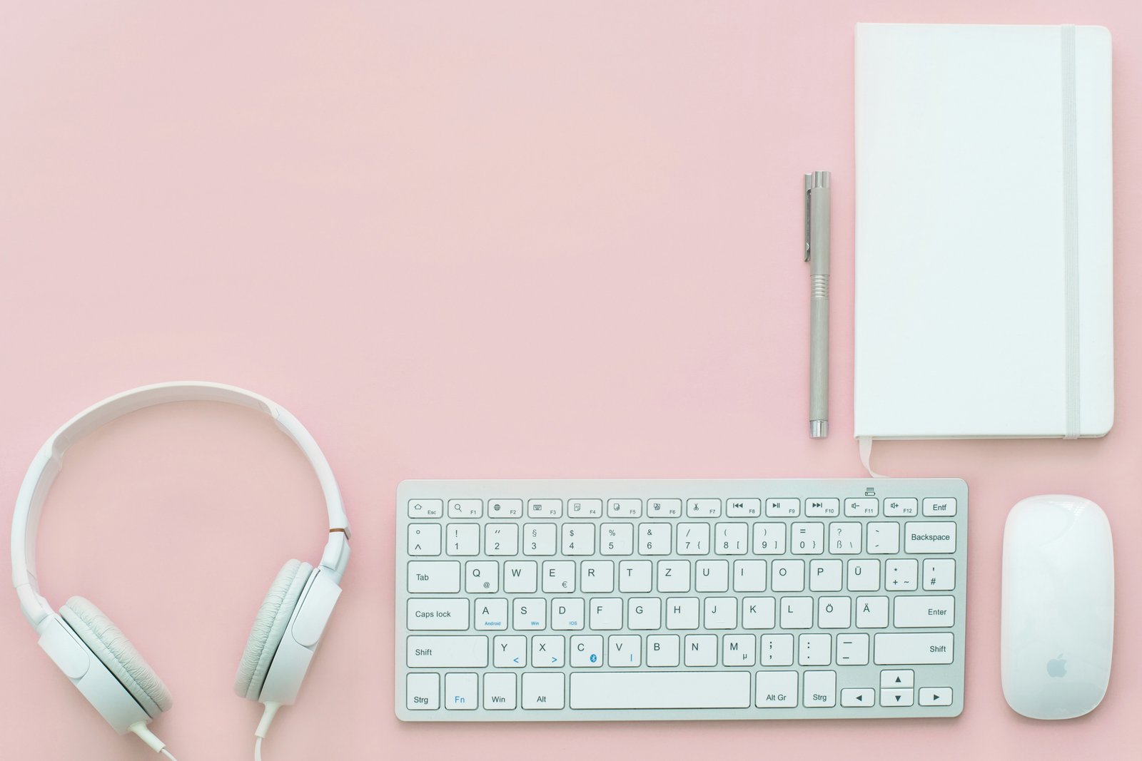 Notebook, keyboard, headphones, and desk accessories representing modern business work